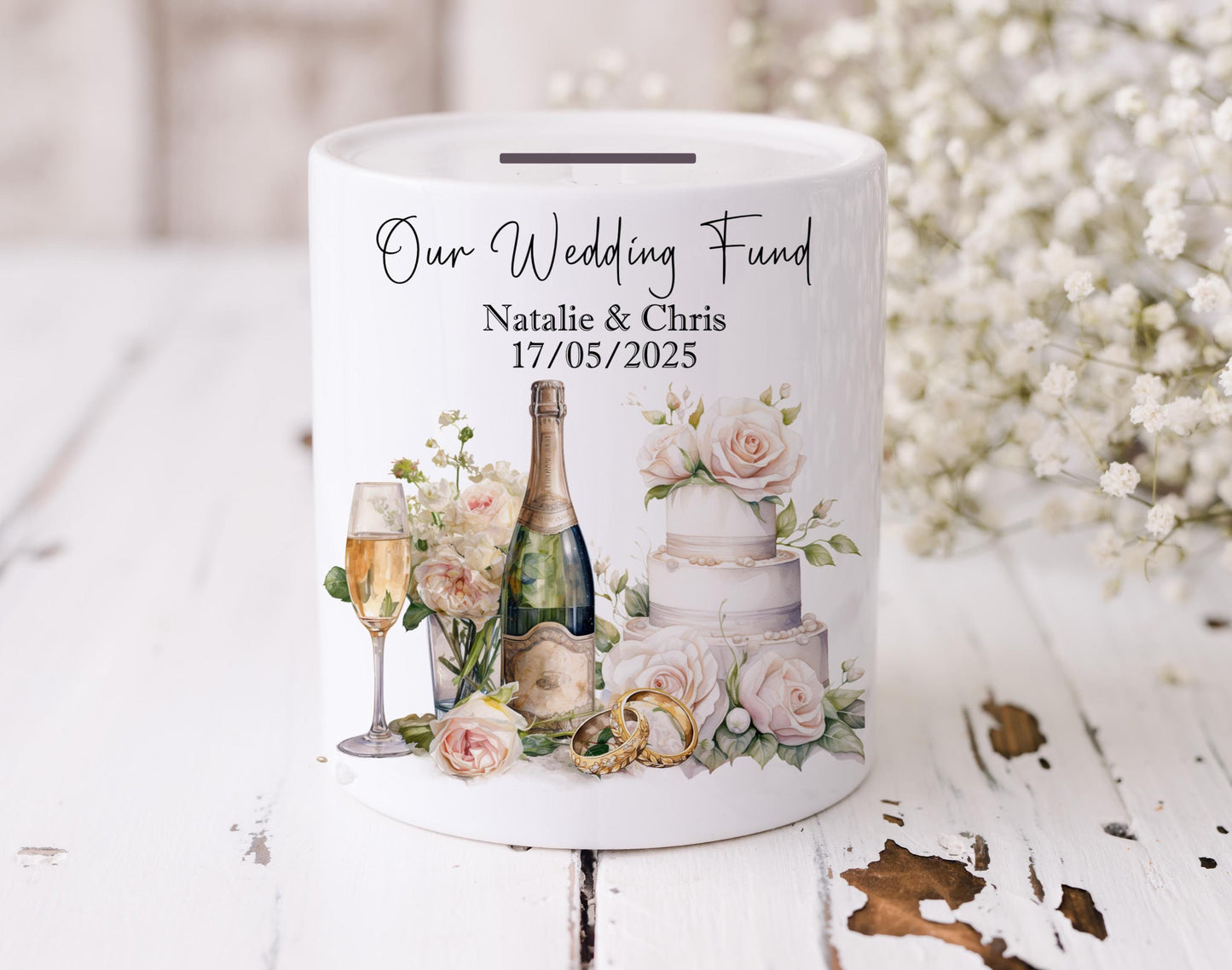 11 ounce ceramic cylinder sharped Wedding Fund Money Box with the couples name and date of their wedding on it. The beautiful watercolour design shows a wedding cake, rings, champagne and florals.