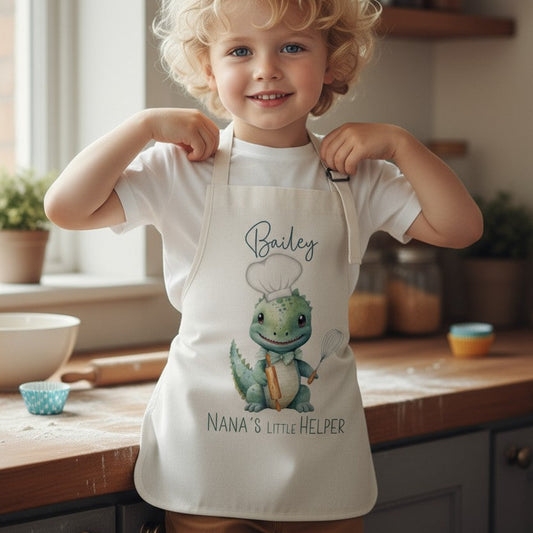 Young boy in beige linen apron with and Dinosaur chef on the front.