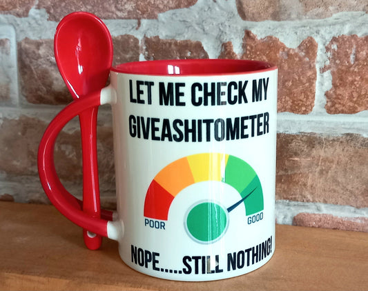 White Ceramic Mug with Red inner and red spoon attached. The image on the front is a meter which goes from poor to good. It reads &#39;Let me Chck my Give a Shit - ometer&#39; which also has this written in black text.