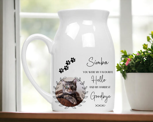 White ceramic vase with handle and a photo of a cat in a frame. The cats name is above the photo and there isa lovely verse which reads You were my favourite hello and my hardest goodbye. There are also pawprints above the photo.