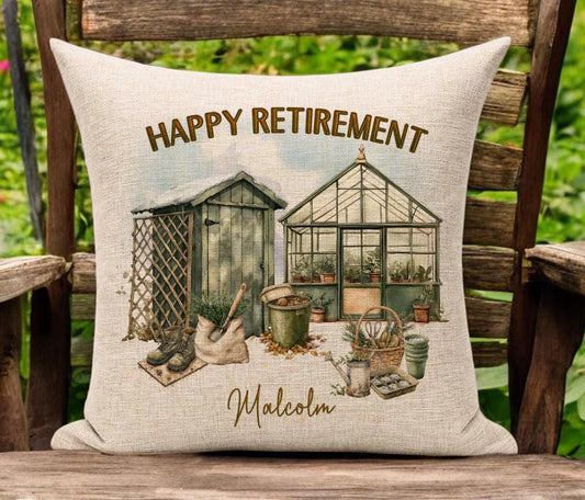 Creamy beige linen cushion sat on a garden chair. The image on the cushion is of a watercolour garden scene with green and brown colours. The text reads Happy Retirement at the top and the recipients name at the bottom which is personable.
