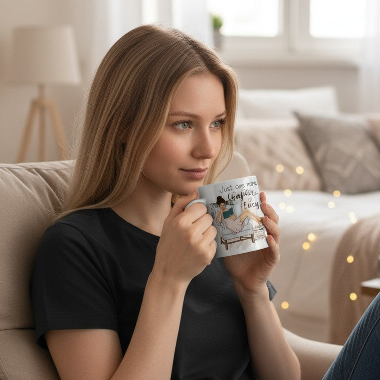Woman sitting on a couch holding a mug with a photo of a lady reading on it, in a cosy living room.